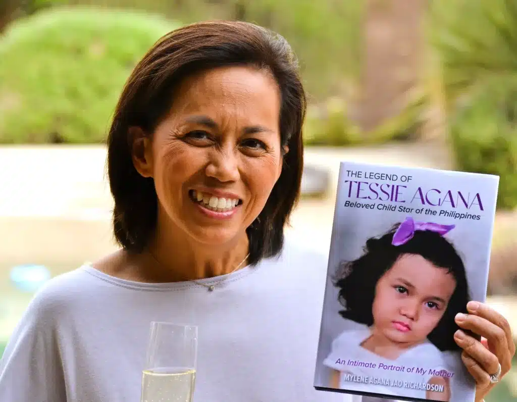 Mylene Richardson holding champagne and her new book 'The Legend of Tessie Agana' 